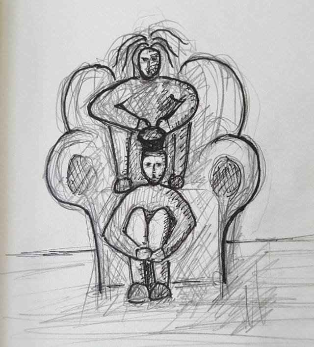 Ein Mann sitzt an ein Sofa gelehnt da. Am Kopf hat er einen runden Gegenstand. Über ihm am Sofa sitzt eine Frau mit struppigem Haar.